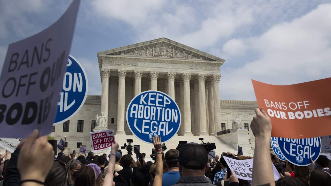 A group of people holding placards protesting outside the United States Supreme Court.