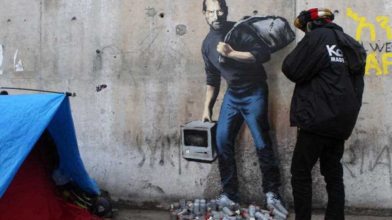 A painting by English graffiti artist Banksy is seen at the entrance of the Calais refugee camp in France