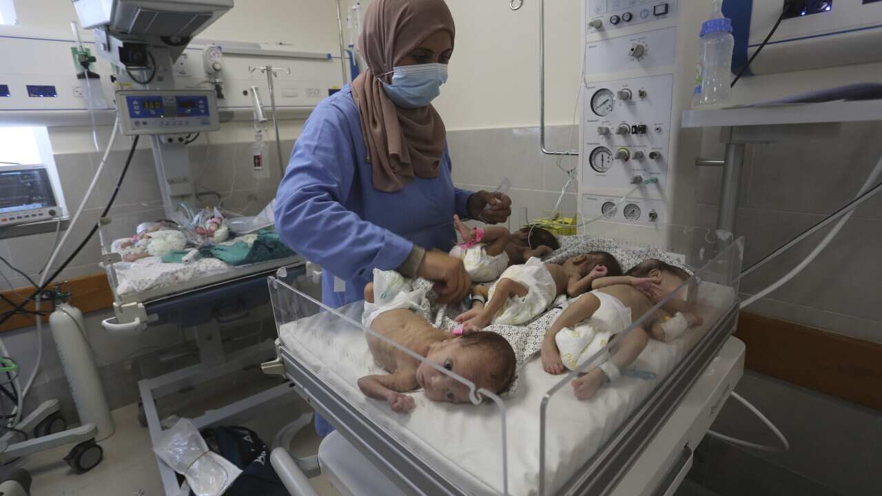 A nurse inspects babies cradled together in hospital