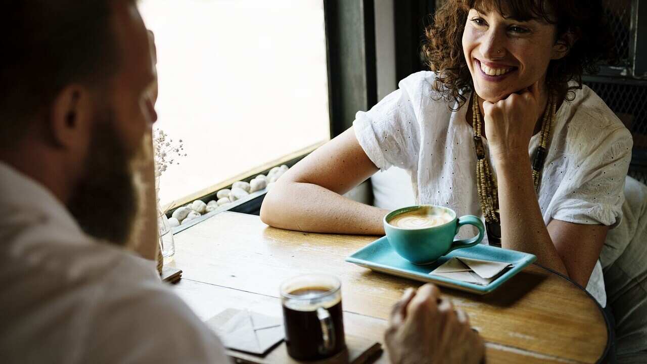 Woman smiling to a man while they're having coffee