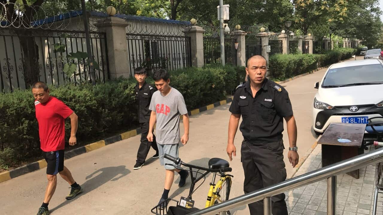 Chinese security guards arrive to stop journalists from entering the apartment building where Liu Xia