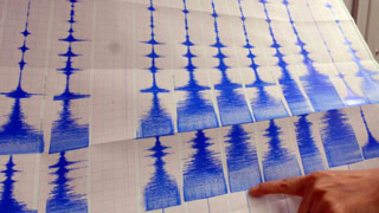 A seismologist points to a graph charting seismic activity