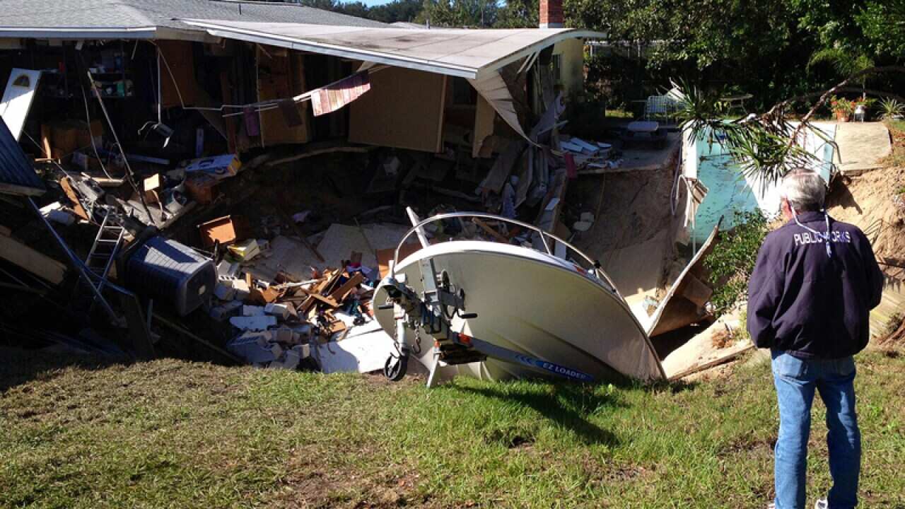 A man observes a sinkhole has swallowed two houses in Dunedin, Fla.