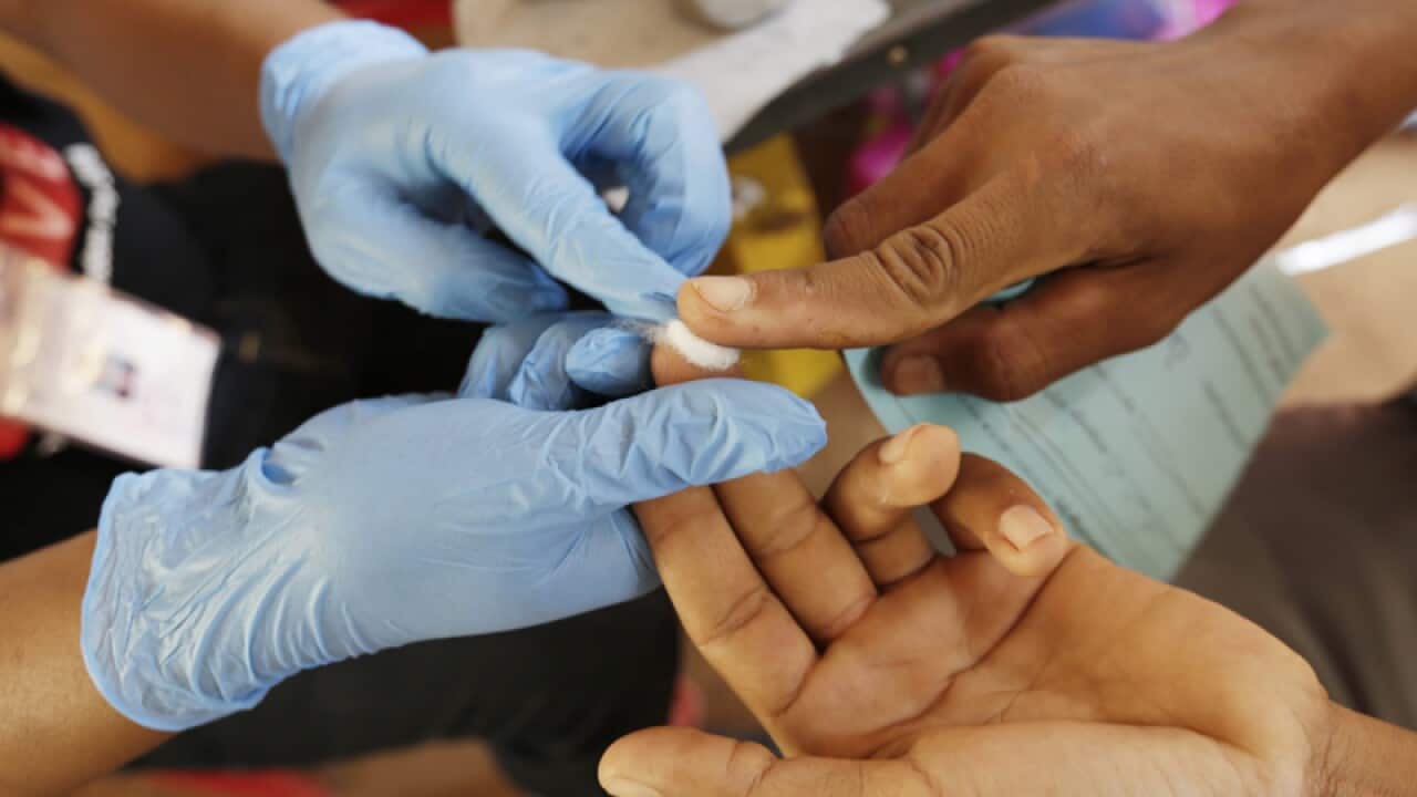 A Cambodian health worker takes blood from a villager to test for HIV