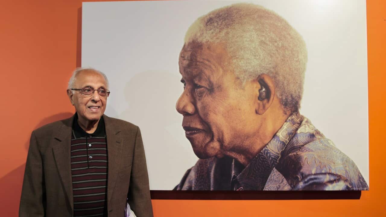 Ahmed Kathrada poses in front of picture of late South African president Nelson Mandela