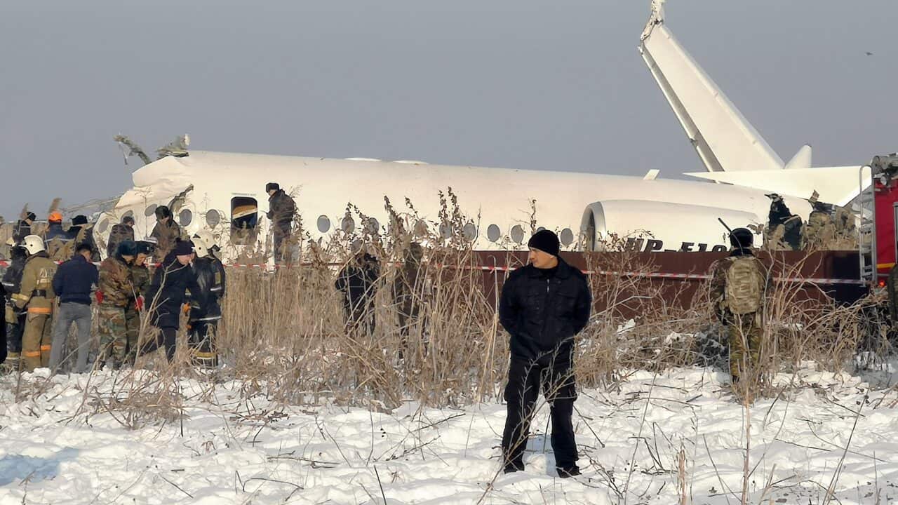 Police stand guard as rescuers work on the side of a plane crash near Almaty International Airport, outside Almaty, Kazakhstan.