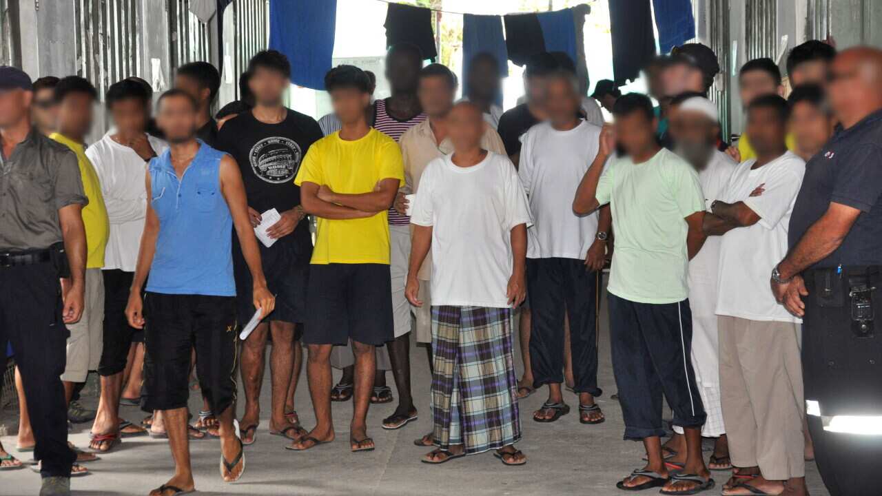 Asylum seekers in Delta compound watch as a court appointed party inspects Australias Manus Island detention centre in Papua New Guinea, Friday, March 21, 2014. Papua New Guinea expects to start resettling refugees detained in Australia's offshore process