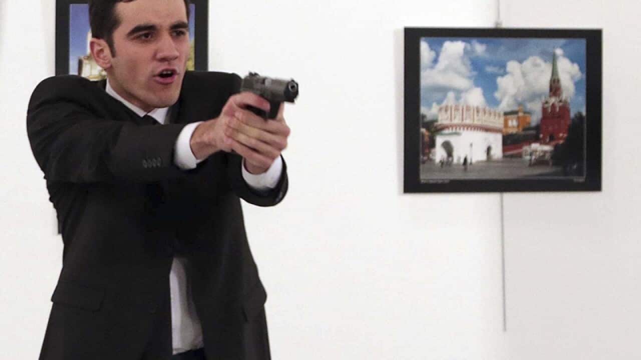 A gunman points his gun, after shooting the Russian Ambassador