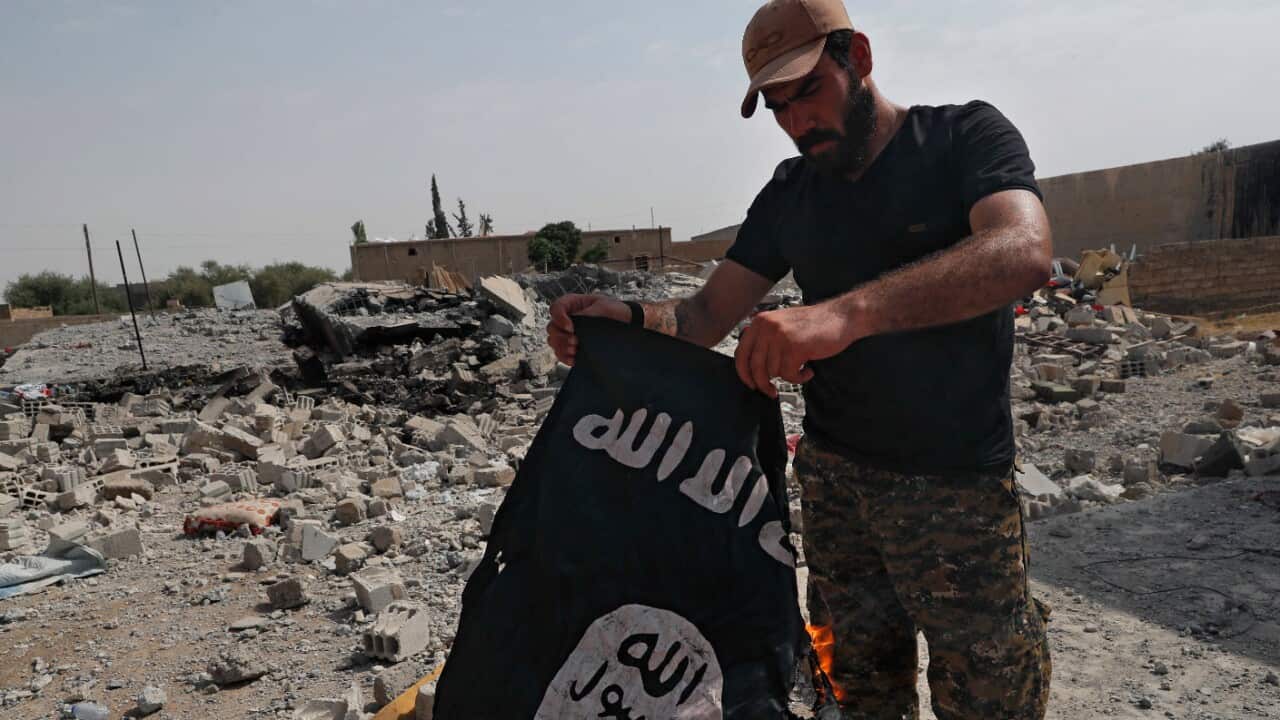 A man holds a burning Islamic State flag.