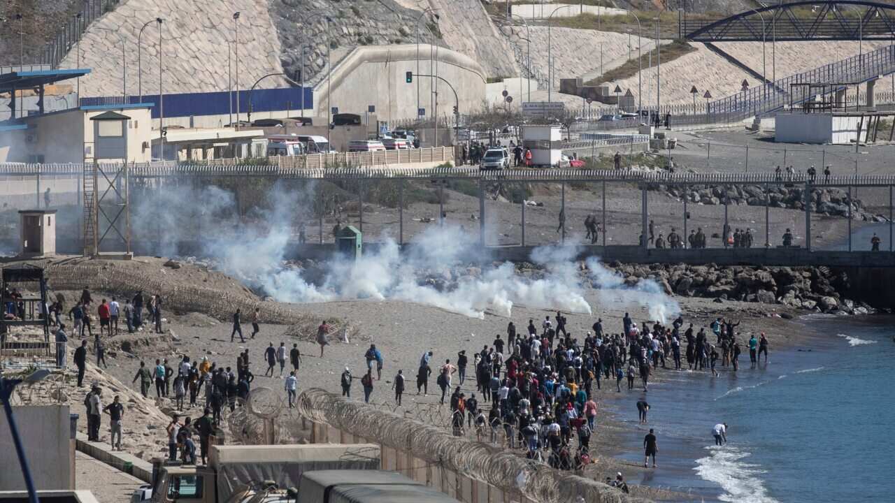 Spanish security forces throw tear gas at Moroccan and sub-saharan migrants attempting to cross the fence of the Spanish enclave of Ceuta.