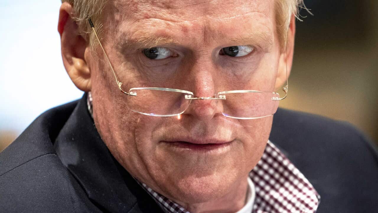 A man with red hair wears glasses on the end of his nose