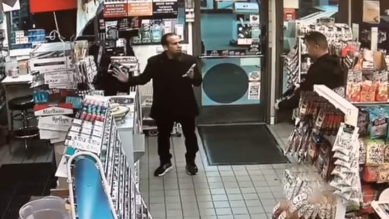 Screenshot from a video of Jose Arreola, center, paying for a roll of Mentos in a California petrol station when the police officer, right, pulled out a gun