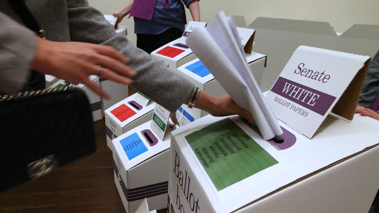 Mpiga kura atumbukiza kura yake, ndani ya sanduku la kura za Seneti.