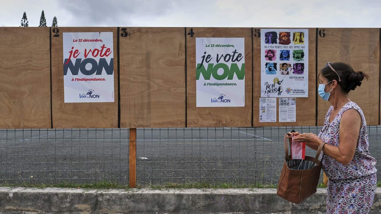 A woman walks past electoral posters calling to vote No to the referendum