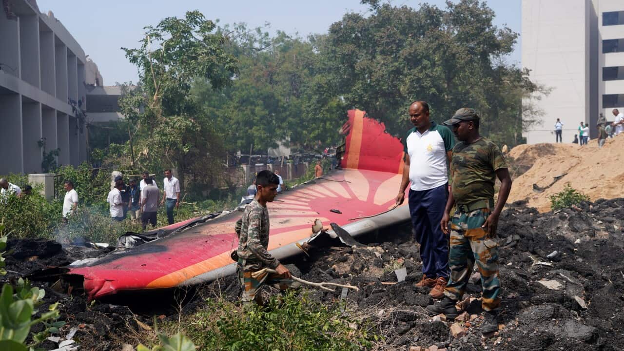 People standing near part of an aircraft that crashed.