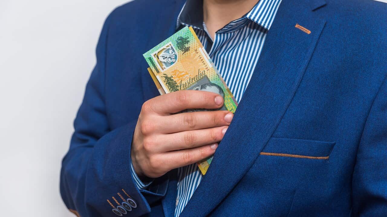Male hand hiding Australian banknotes in pocket