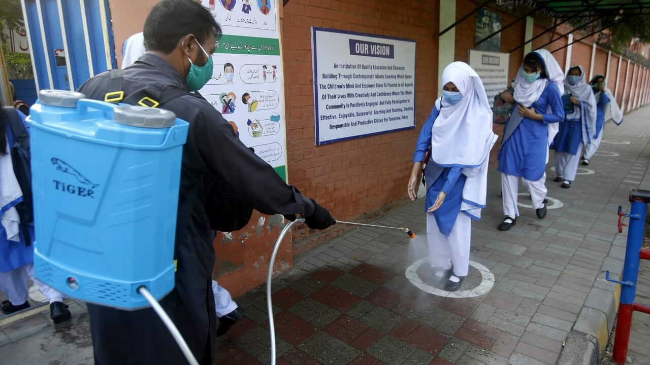 A worker disinfects the shoes of a student as she arrives at school in Lahore, Pakistan