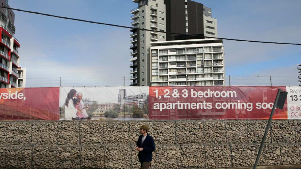 A man walks past a real estate development in Sydney