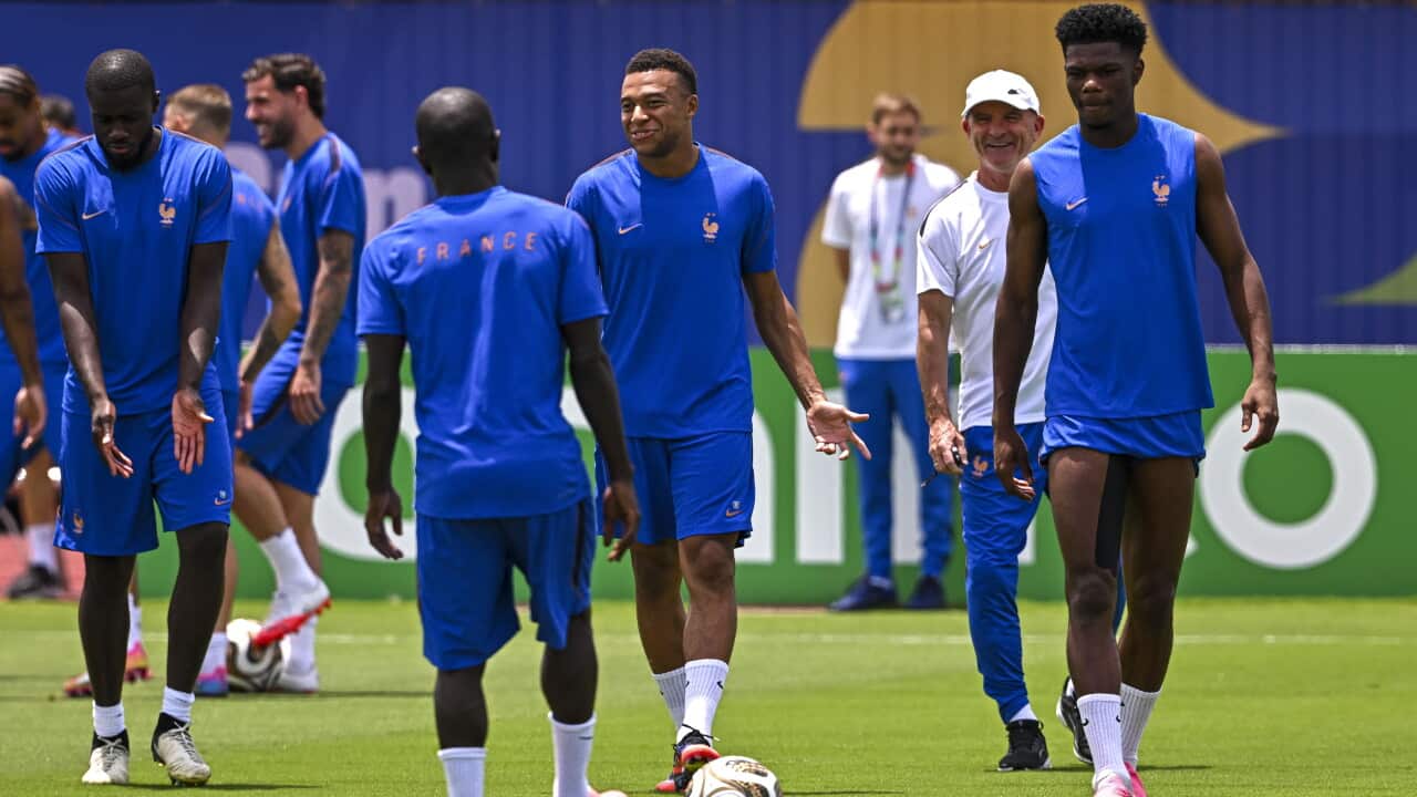 Footballers wearing blue shirts and shorts on a grass training pitch