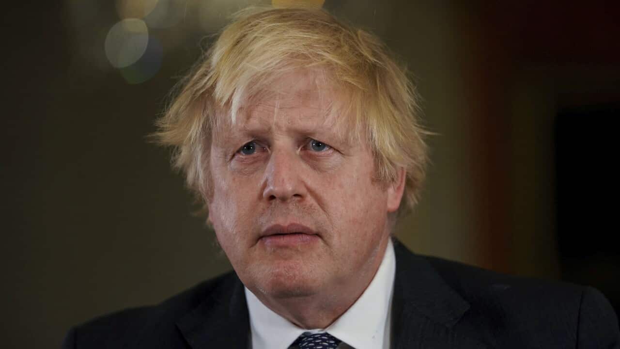 Boris Johnson standing looking sullen