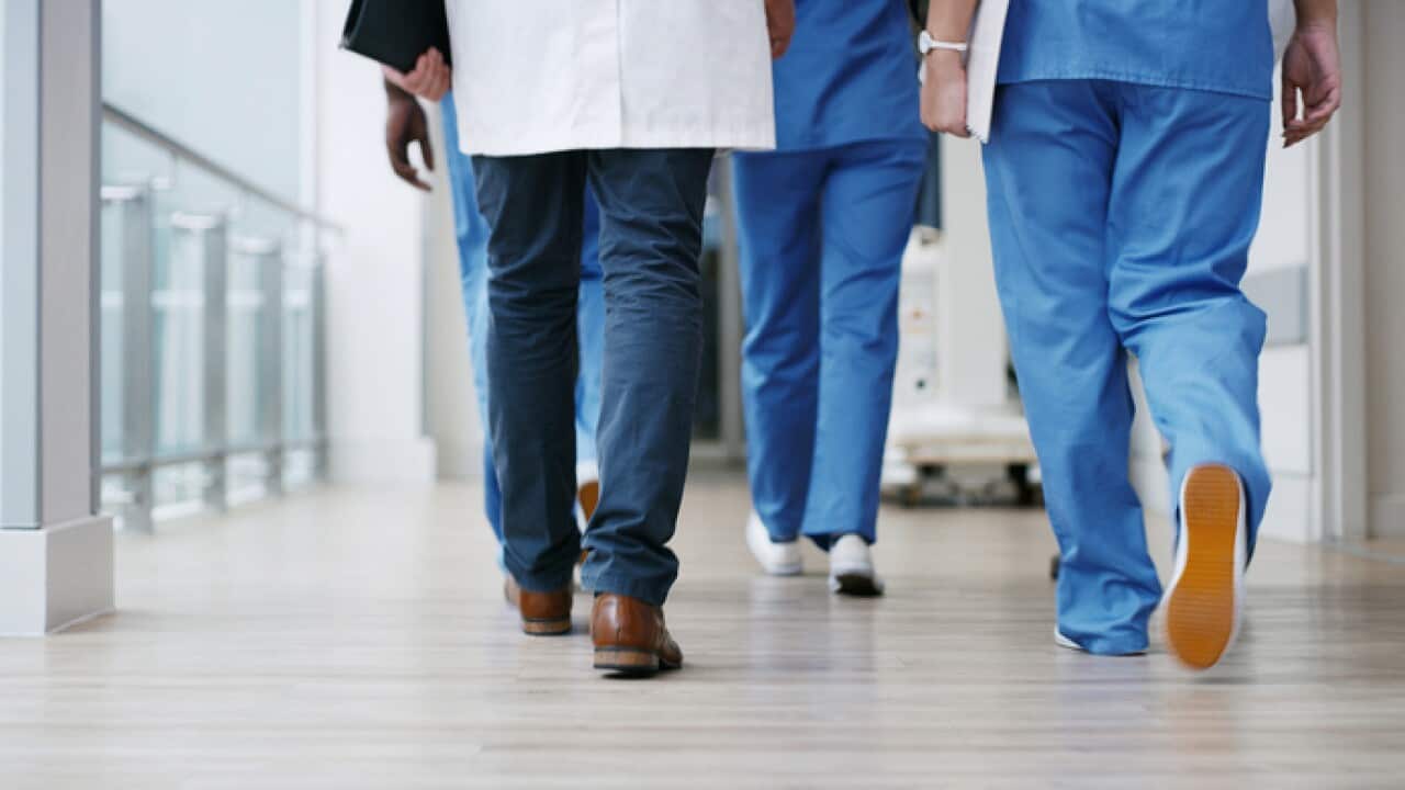 Legs of doctors and nurses walking through a hospital in uniform.