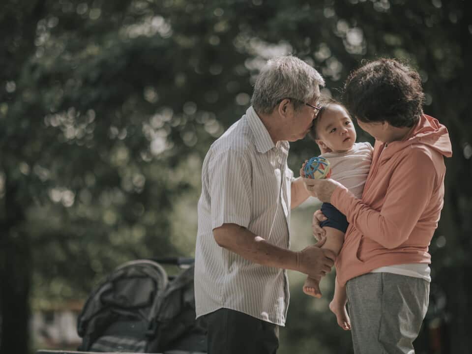 asian chinese grandparent bonding with their baby boy grandchild in public park in the morning