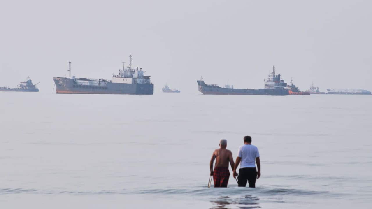 Two men wade in the waters of the Strait of Hormuz with vessels anchored in the background, off Bandar Abbas, Iran (Razieh Poudat-ISNA via AP).jpg