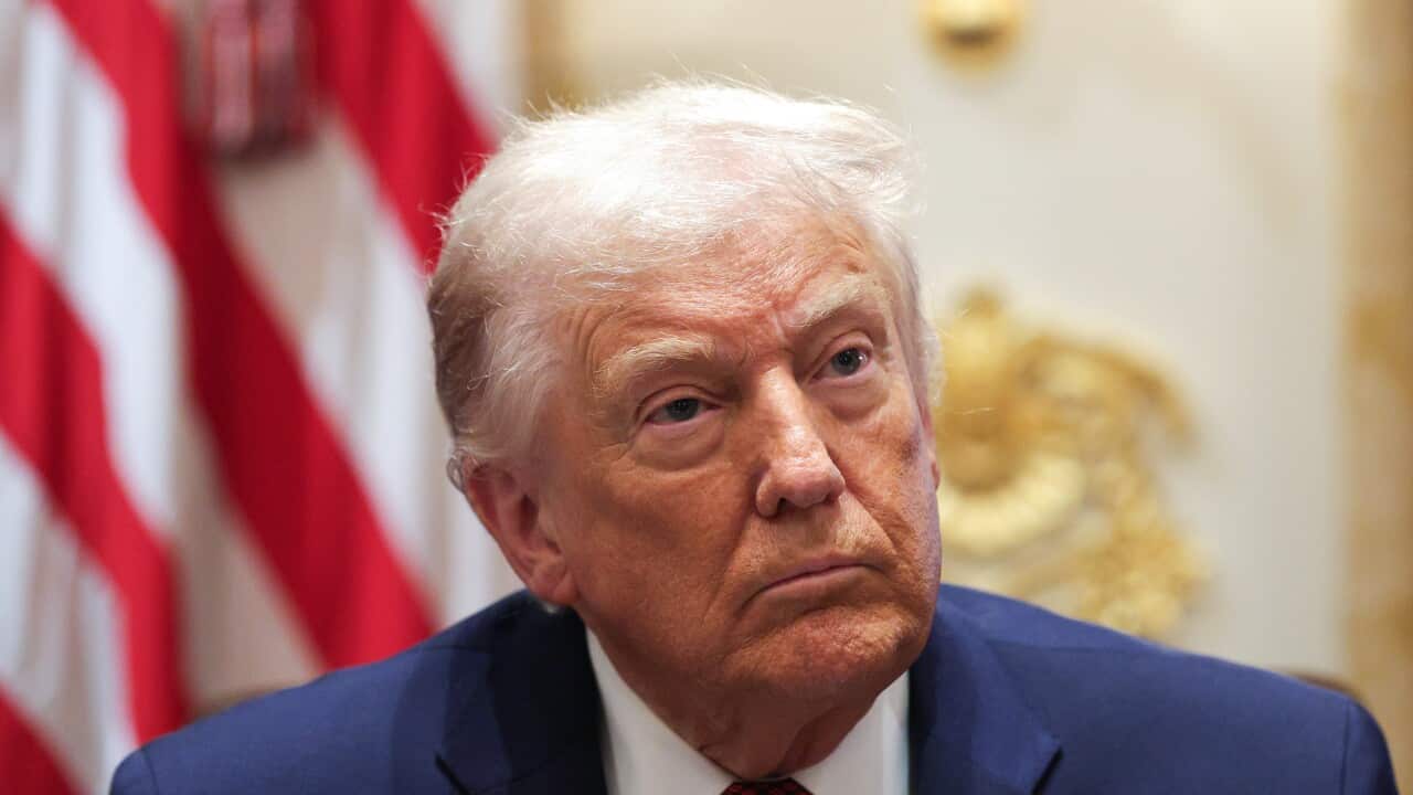 Trump in a blue suit and red tie looking off to the side