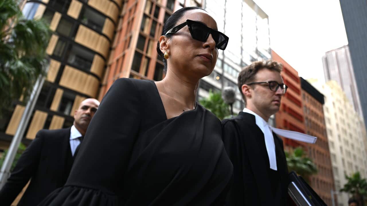 A woman wearing black sunglasses and blazer