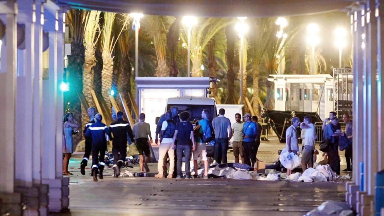 People stand next to covered bodies