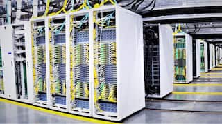 Rows of AI data processing computers stand inside a large warehouse.