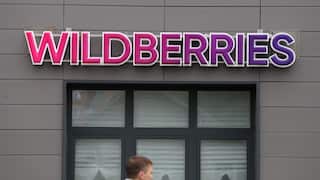 A man walking past a building with 'Wildberries' signage on it.