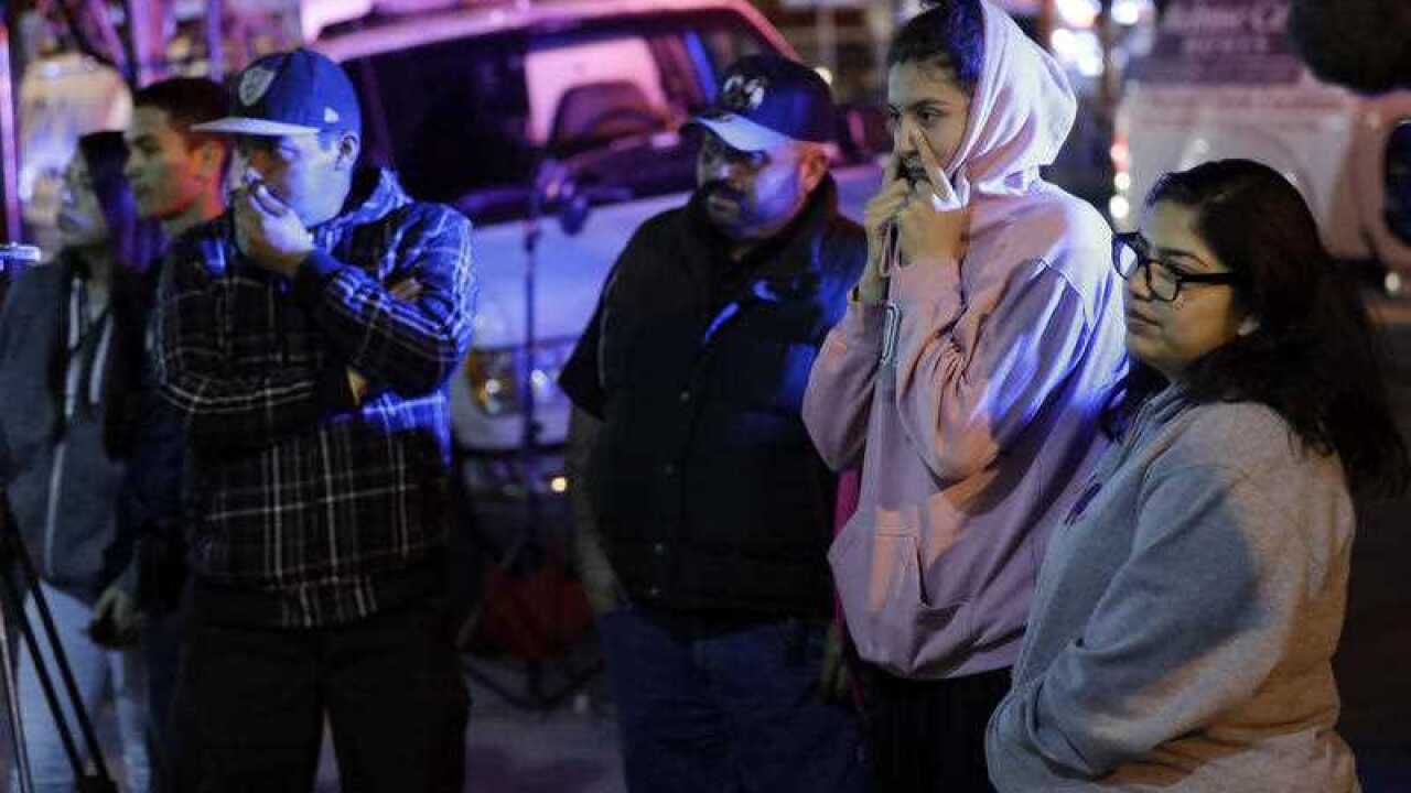 People watch as firefighters and emergency crews work the site of a warehouse fire .