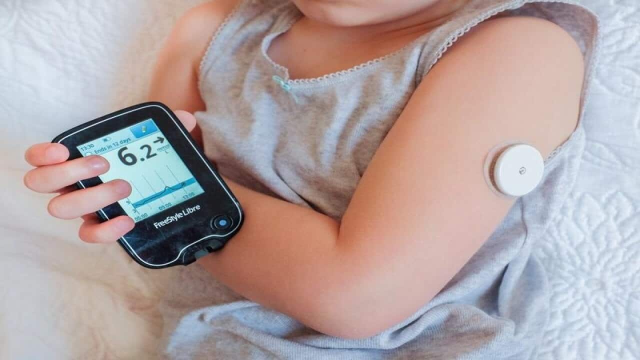 A child checks her blood sugar by using a sensor device.