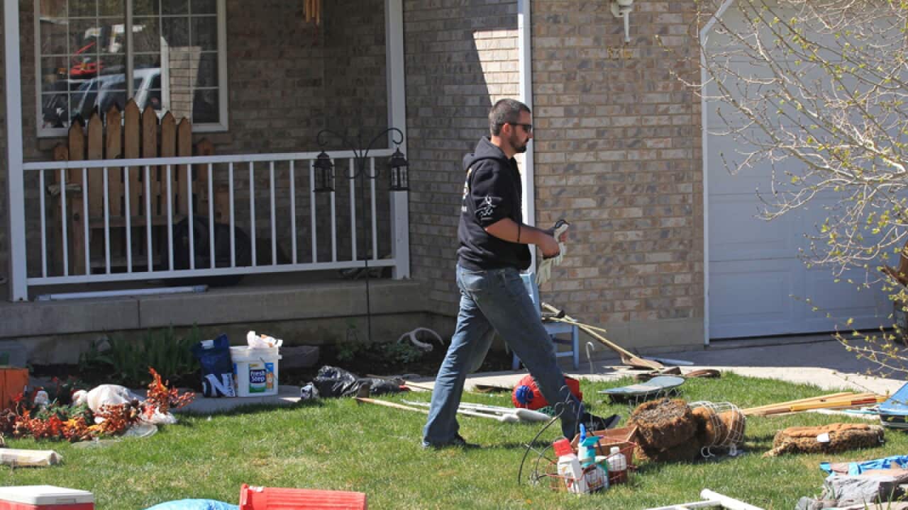 An unidentified person walks through the front yard of a house