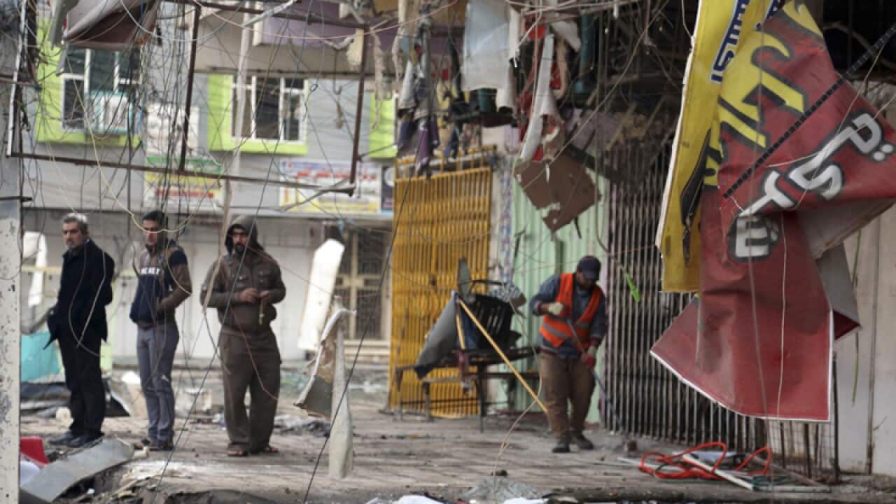 People inspect the remains after a car bomb attack in Iraq