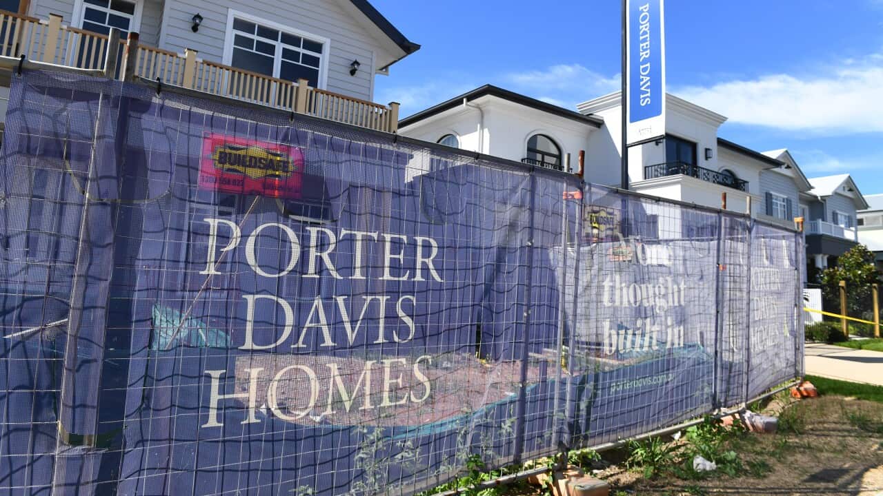 Temporary fencing with signage that reads "PORTER DAVIS HOMES" surrounds a house.