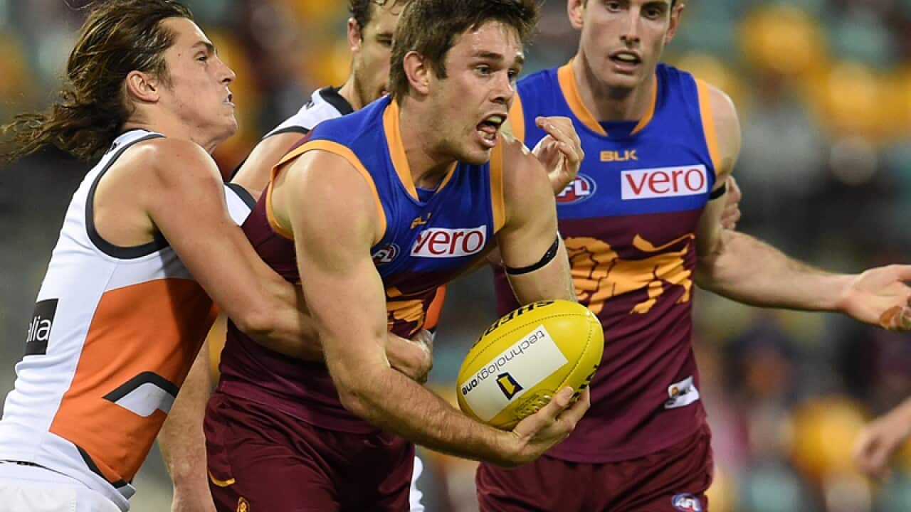 Ryan Bastinac of the Brisbane Lions (C) is tackled by Phil Davis