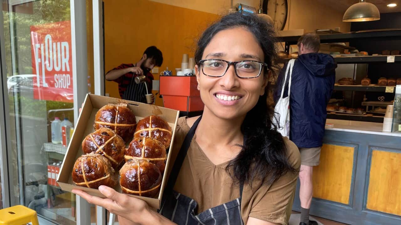 Female baker in Sydney holding up a box of six hot cross buns
