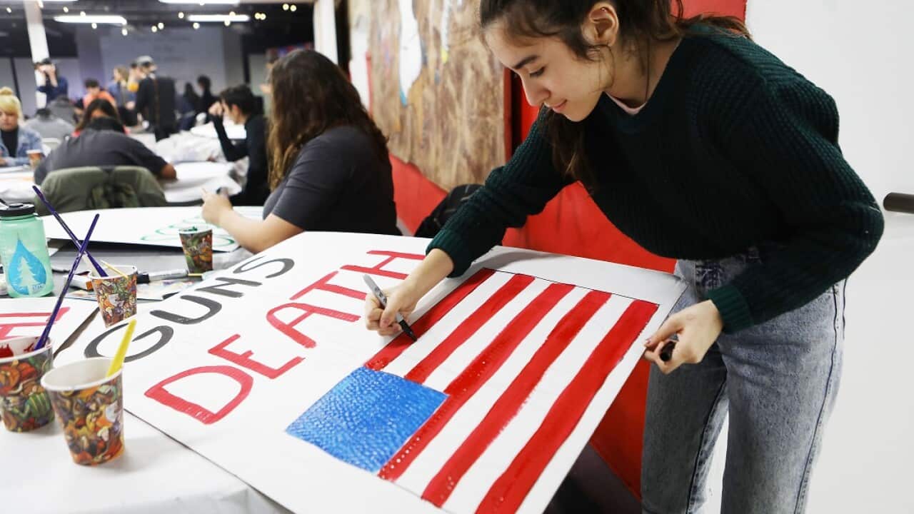 A student paints a sign for the upcoming March for Our Lives rally.