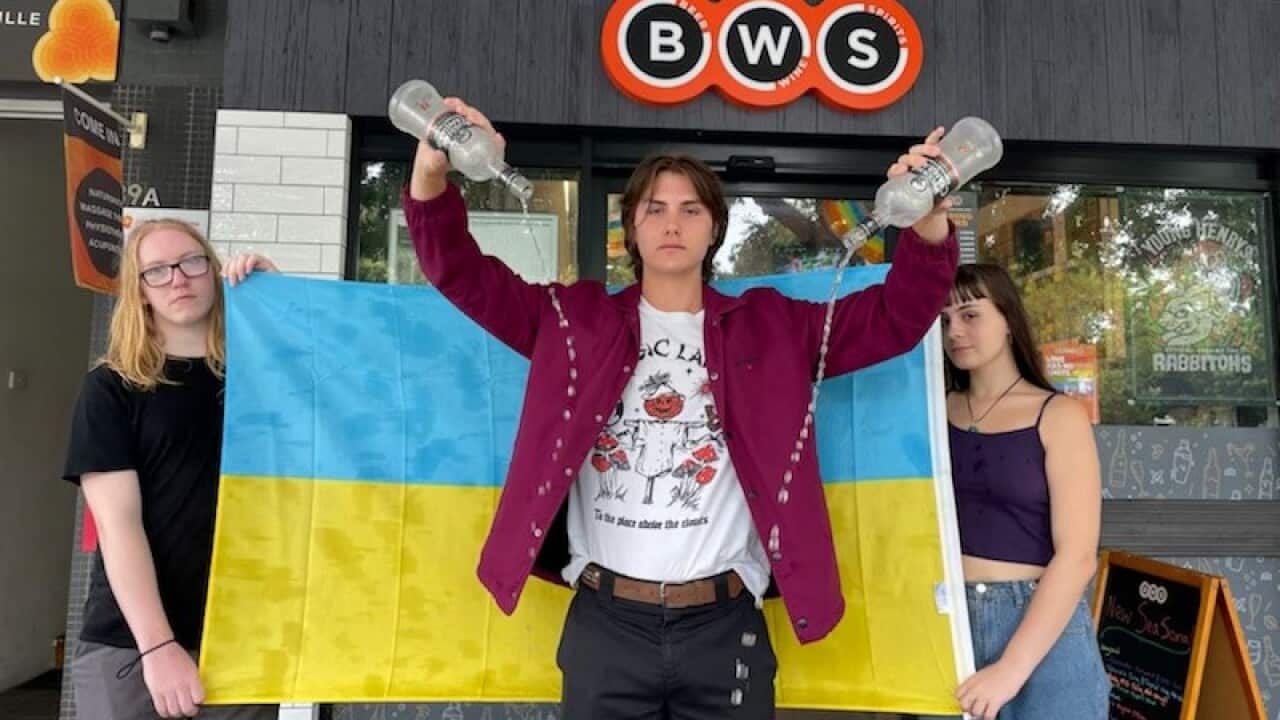 Seb Richardson, Max O'Keefe and Ella O'Shea empty bottles of Russian vodka out the front of a BWS store in Erskineville, NSW, on Tuesday, 1 March.