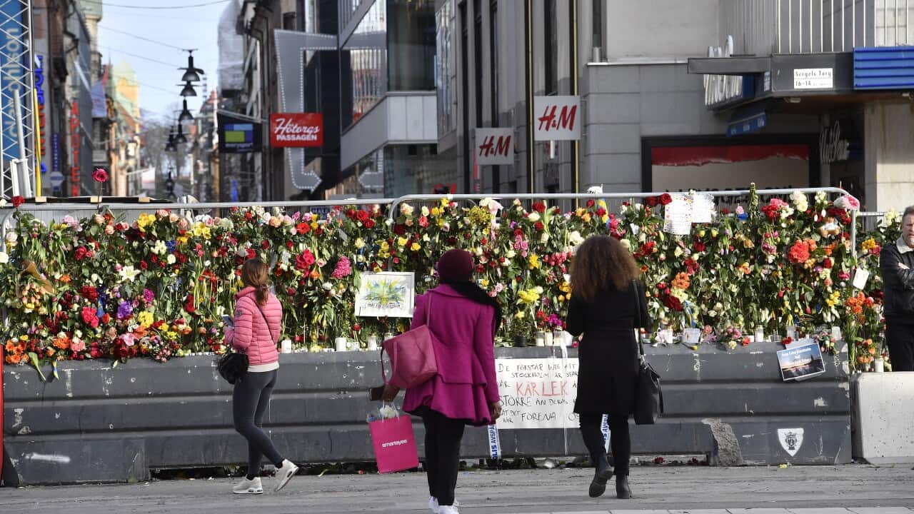 People visit floral tributes on a fence by a department store near the scene of a truck attack in Stockholm.