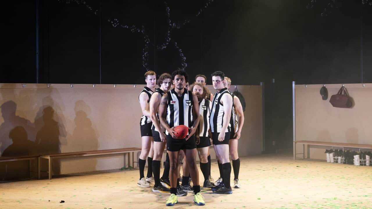 A group of men standing on stage, one holding a football.