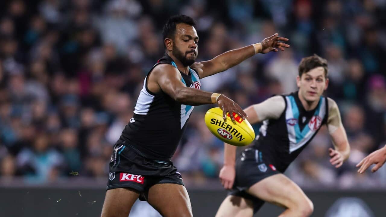 An Aboriginal Port Adelaide AFL player kicks a ball