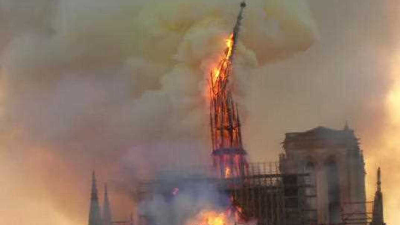Flames and smoke rise as the spire of Notre Dame cathedral collapses.