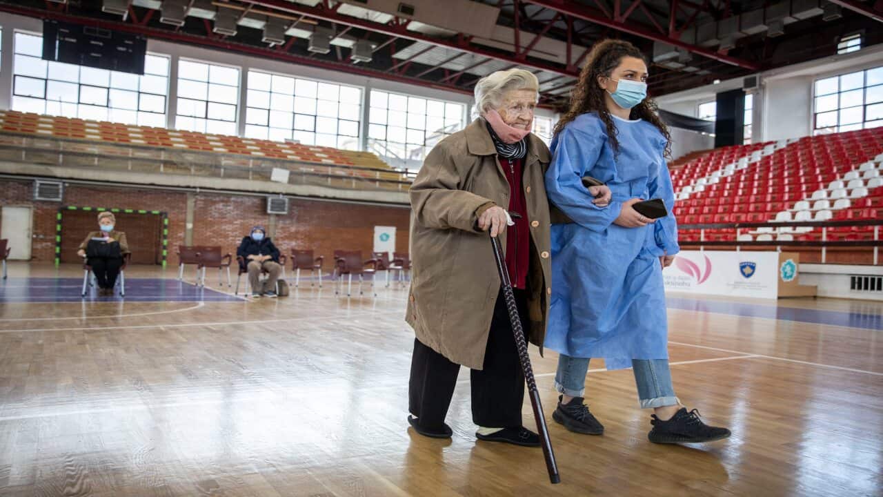 An elderly woman is being accompanied before receiving a dose of the AstraZeneca vaccine from Kosovo’s first COVAX supply as the nation begins its rollout for people aged over 85 on 8 April.