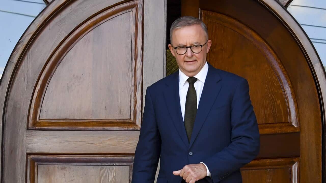 Anthony Albanese exits the door of a church wearing a suit.