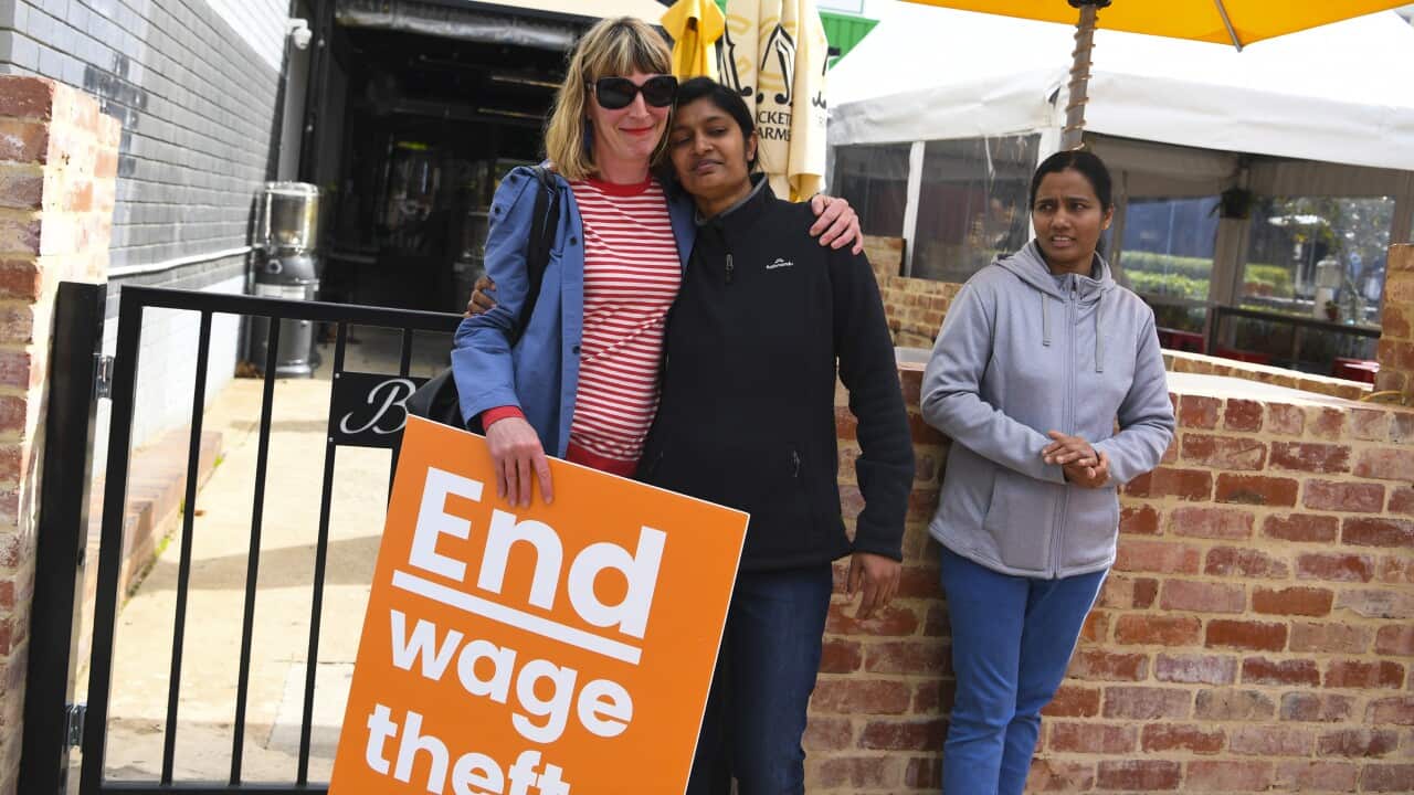 Former employees Shojin Thomas (centre) and Ninumol Abraham are seen near the Indian Restaurant Binny's Kathitto in Canberra.