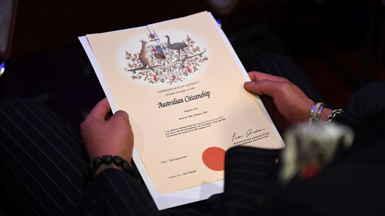 An Australian citizenship recipient holds his certificate during a citizenship ceremony on Australia Day