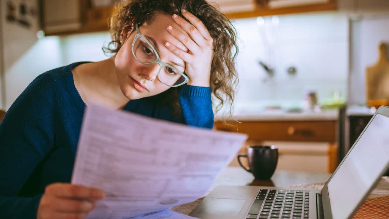 Woman going through bills, looking worried.